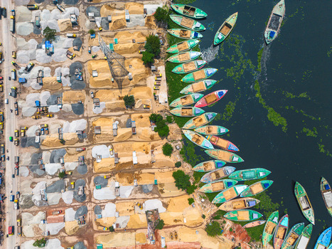 Aerial view of boats docked along the water s edge contrasting with piles of materials on the land creating a vibrant scene Dhaka Dhaka Division Bangladesh. Aerial view of boats docked along the water s edge contrasting with piles of materials on the land creating a vibrant scene Dhaka Dhaka Division Bangladesh.