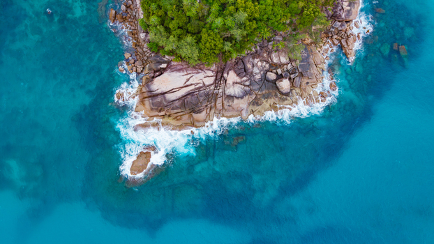 Aerial view of the rocky coastline of Grand Anse Mahe with lush tropical vegetation meeting the turquoise waters of the Indian Ocean in Grand Anse Mahe Seychelles. Aerial view of the rocky coastline of Grand Anse Mahe with lush tropical vegetation meeting the turquoise waters of the Indian Ocean in Grand Anse Mahe Seychelles.