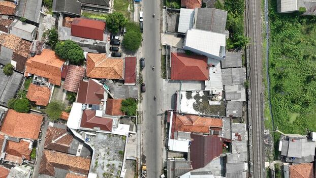 Aerial view of a residential neighborhood with red tiled roofs a central road and adjacent railway tracks in Kasemen Banten Indonesia. Aerial view of a residential neighborhood with red tiled roofs a central road and adjacent railway tracks in Kasemen Banten Indonesia.