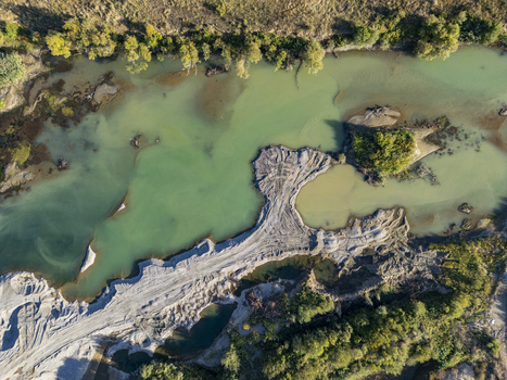 Aerial view of the Buna Drin River Confluence showing the meeting of two rivers with distinct water colors sandbanks and surrounding lush vegetation in Zues Qarku i Shkodres Albania.
