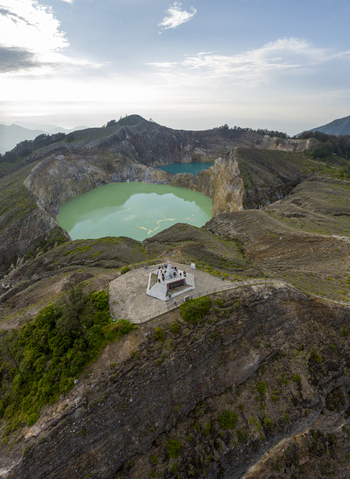 Aerial view of the volcanic crater lakes of Kelimutu National Park with turquoise and green water an observation deck and rugged terrain in Detusoko East Nusa Tenggara Indonesia.