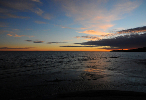 View of the sunset over the calm ocean waters at Puerto Piramides with orange light on the horizon and soft clouds in the sky Puerto Madryn Chubut Argentina. View of the sunset over the calm ocean waters at Puerto Piramides with orange light on the horizon and soft clouds in the sky Puerto Madryn Chubut Argentina.