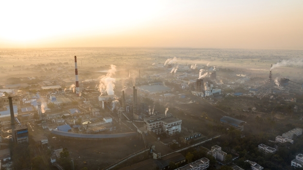 Aerial view of an industrial plant with smokestacks emitting smoke into the hazy sky during golden hour in Nagda Madhya Pradesh India. Aerial view of an industrial plant with smokestacks emitting smoke into the hazy sky during golden hour in Nagda Madhya Pradesh India.