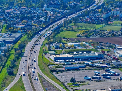 Aerial view of the bustling highway cutting through the green landscape and industrial buildings Sausheim Grand Est France.