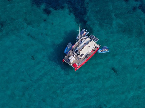 Aerial view of a red catamaran anchored in the clear turquoise waters near Ile Sainte Marguerite Cannes Provence Alpes Cote d Azur France. Aerial view of a red catamaran anchored in the clear turquoise waters near Ile Sainte Marguerite Cannes Provence Alpes Cote d Azur France.