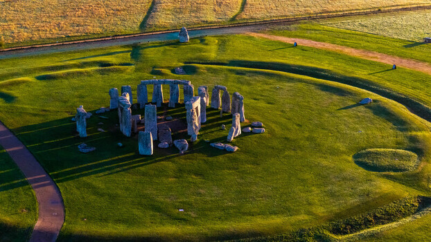 Aerial view of the ancient Stonehenge monument surrounded by lush green fields and long shadows during the golden hour in Salisbury England United Kingdom. Aerial view of the ancient Stonehenge monument surrounded by lush green fields and long shadows during the golden hour in Salisbury England United Kingdom.