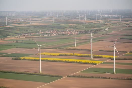 Aerial view of wind turbines standing in a patchwork of green and yellow agricultural fields near a small village in Lower Austria Austria. Aerial view of wind turbines standing in a patchwork of green and yellow agricultural fields near a small village in Lower Austria Austria.