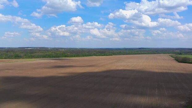 Aerial view of plowed farmland under a cloudy blue sky United States. Aerial view of plowed farmland under a cloudy blue sky United States.