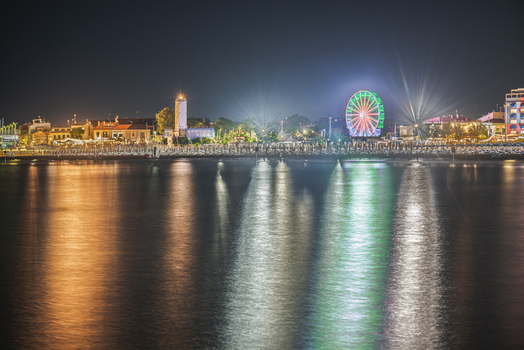 View of the illuminated Ferris wheel and lighthouse reflecting on the calm water of the Adriatic Sea at night in Fano Marche Italy. View of the illuminated Ferris wheel and lighthouse reflecting on the calm water of the Adriatic Sea at night in Fano Marche Italy.