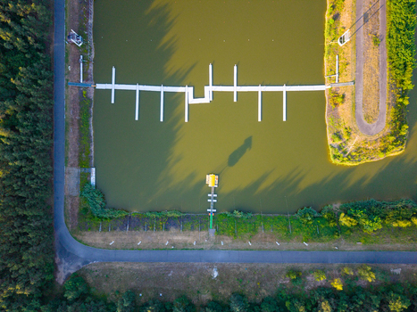 Aerial view of Labe Arena Racice featuring a long floating dock on calm water surrounded by dense forest and paved paths Racice Ustecky kraj Czechia. Aerial view of Labe Arena Racice featuring a long floating dock on calm water surrounded by dense forest and paved paths Racice Ustecky kraj Czechia.