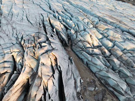 Aerial view of Svinafellsjokull glacier with deep blue crevasses and rugged ice formations in Sveitarfelagid Hornafjordur Iceland. Aerial view of Svinafellsjokull glacier with deep blue crevasses and rugged ice formations in Sveitarfelagid Hornafjordur Iceland.