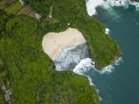 Aerial view of Sedahan Beach s secluded cove where turquoise waters meet the soft sandy shore embraced by lush green cliffs Gunungkidul Regency Special Region of Yogyakarta Indonesia. Aerial view of Sedahan Beach s secluded cove where turquoise waters meet the soft sandy shore embraced by lush green cliffs Gunungkidul Regency Special Region of Yogyakarta Indonesia.