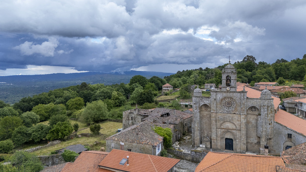 Aerial view of Iglesia de Santa Marina de Augas Santas with its stone facade and bell tower surrounded by traditional houses and lush green forests Augas Santas Ourense Spain. Aerial view of Iglesia de Santa Marina de Augas Santas with its stone facade and bell tower surrounded by traditional houses and lush green forests Augas Santas Ourense Spain.