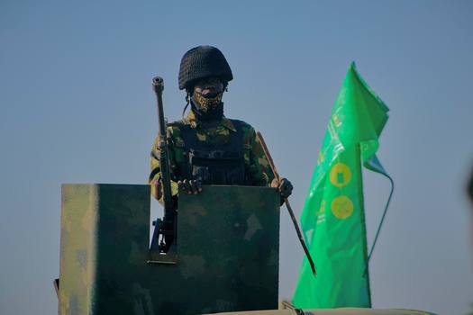 Zaria Nigeria 21 March 2026 View of a vigilant soldier in camouflage stark against the clear sky standing guard from a military vehicle with a bright green flag fluttering nearby. Zaria Nigeria 21 March 2026 View of a vigilant soldier in camouflage stark against the clear sky standing guard from a military vehicle with a bright green flag fluttering nearby.