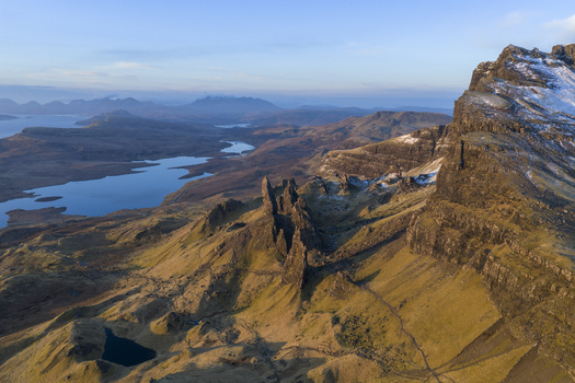 Aerial view of The Storr featuring its iconic rock pinnacles snow dusted peaks and distant lochs under a clear sky Isle of Skye Scotland United Kingdom. Aerial view of The Storr featuring its iconic rock pinnacles snow dusted peaks and distant lochs under a clear sky Isle of Skye Scotland United Kingdom.