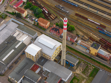 Aerial view of an industrial complex featuring a tall red and white striped chimney and factory buildings near railway tracks in Breclav South Moravian Region Czechia.