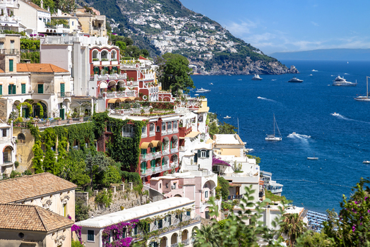 Aerial view of the colorful houses of Positano cascading down the cliffs towards the Mediterranean Sea with boats sailing on the blue water in Positano Campania Italy. Aerial view of the colorful houses of Positano cascading down the cliffs towards the Mediterranean Sea with boats sailing on the blue water in Positano Campania Italy.