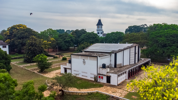 Aerial view of Achimota School featuring a prominent white building with solar panels a historic clock tower in the background and lush green trees in Achimota Greater Accra Region Ghana. Aerial view of Achimota School featuring a prominent white building with solar panels a historic clock tower in the background and lush green trees in Achimota Greater Accra Region Ghana.