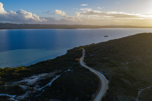 Aerial view of the winding coastal road near Camp Quaranup surrounded by native vegetation and overlooking the calm blue waters of the bay in Vancouver Peninsula Western Australia Australia. Aerial view of the winding coastal road near Camp Quaranup surrounded by native vegetation and overlooking the calm blue waters of the bay in Vancouver Peninsula Western Australia Australia.