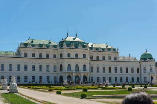 View of the Upper Belvedere Palace with its baroque architecture and green copper roofs overlooking manicured gardens and people walking under a clear blue sky in Vienna Vienna Austria. View of the Upper Belvedere Palace with its baroque architecture and green copper roofs overlooking manicured gardens and people walking under a clear blue sky in Vienna Vienna Austria.