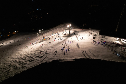 Aerial view of Les Crosets ski resort at night with skiers on illuminated slopes and ski lift towers in Val d Illiez Valais Switzerland. Aerial view of Les Crosets ski resort at night with skiers on illuminated slopes and ski lift towers in Val d Illiez Valais Switzerland.
