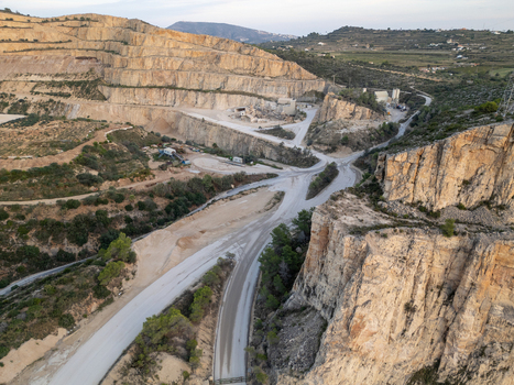 Aerial view of a large open pit quarry in Teulada showing terraced rock faces gravel roads and industrial infrastructure in the Valencian Community Spain.