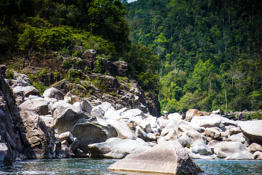 Meghalaya India 31 March 2023 View of the rocky riverbed of the Umngot River in Dawki featuring large smooth boulders clear water and lush green forest covered hills. Meghalaya India 31 March 2023 View of the rocky riverbed of the Umngot River in Dawki featuring large smooth boulders clear water and lush green forest covered hills.