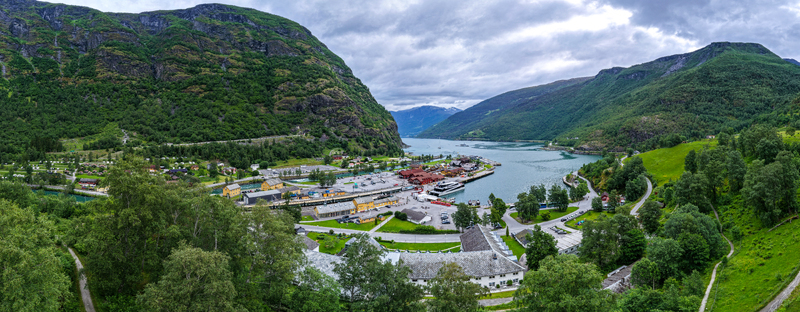 Aerial view of the village of Flam nestled in the Aurlandsfjord surrounded by lush green mountains and dramatic cliffs in Flam Vestland Norway. Aerial view of the village of Flam nestled in the Aurlandsfjord surrounded by lush green mountains and dramatic cliffs in Flam Vestland Norway.