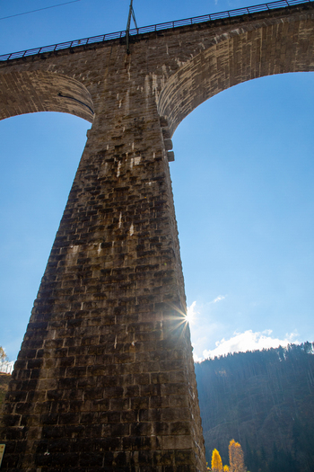 View of the massive stone arches of the Ravennaschlucht viaduct with a sun starburst against a clear blue sky in Breitnau Baden Wurttemberg Germany. View of the massive stone arches of the Ravennaschlucht viaduct with a sun starburst against a clear blue sky in Breitnau Baden Wurttemberg Germany.