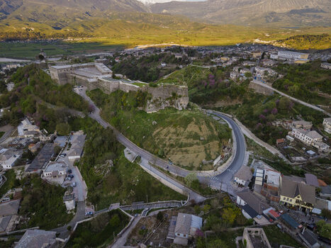 Aerial view of Gjirokaster Fortress overlooking the historic stone city with winding roads and surrounding hills in Gjirokaster Gjirokaster County Albania. Aerial view of Gjirokaster Fortress overlooking the historic stone city with winding roads and surrounding hills in Gjirokaster Gjirokaster County Albania.