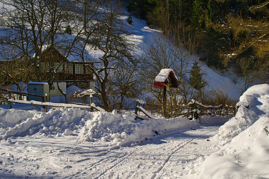 View of a snow covered landscape with a rustic wooden fence and a quaint house nestled among the trees in winter Moce Banska Bystrica Region Slovakia.