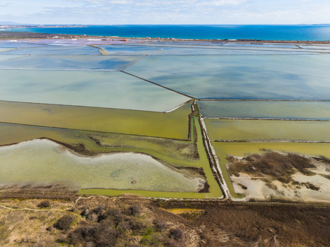 Aerial view of the colorful salt evaporation ponds of Lake Atanasovsko with geometric dikes and the Black Sea coast in the distance Burgas Burgas Bulgaria. Aerial view of the colorful salt evaporation ponds of Lake Atanasovsko with geometric dikes and the Black Sea coast in the distance Burgas Burgas Bulgaria.