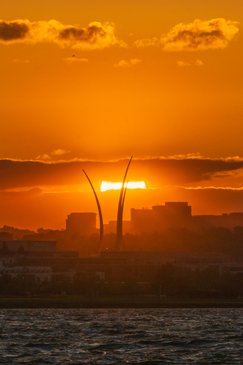View of the Air Force Memorial spires silhouetted against a vibrant orange sunset over the Potomac River and city skyline in Washington District of Columbia United States. View of the Air Force Memorial spires silhouetted against a vibrant orange sunset over the Potomac River and city skyline in Washington District of Columbia United States.