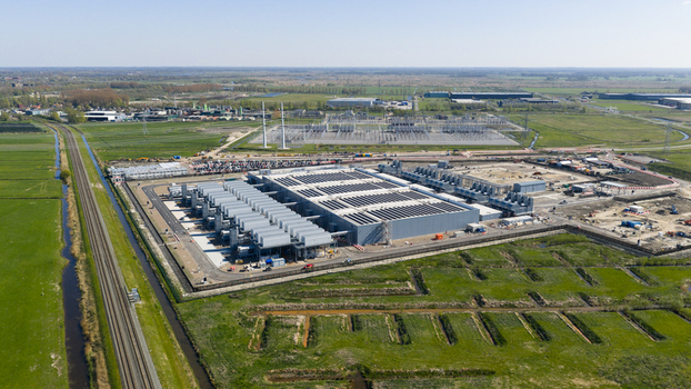 Aerial view of Datacenter Westpoort featuring large industrial cooling units and surrounding green fields with a railway track in Groningen Groningen Netherlands. Aerial view of Datacenter Westpoort featuring large industrial cooling units and surrounding green fields with a railway track in Groningen Groningen Netherlands.