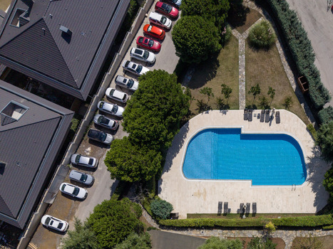 Aerial view of a swimming pool surrounded by a stone deck lush green trees and a row of parked cars in a residential area in Istanbul Istanbul Turkiye. Aerial view of a swimming pool surrounded by a stone deck lush green trees and a row of parked cars in a residential area in Istanbul Istanbul Turkiye.