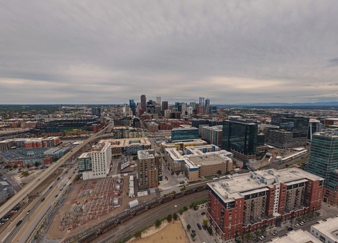 Aerial view of the Denver skyline featuring modern high rise buildings urban infrastructure and surrounding city blocks under a cloudy sky in Denver Colorado United States. Aerial view of the Denver skyline featuring modern high rise buildings urban infrastructure and surrounding city blocks under a cloudy sky in Denver Colorado United States.