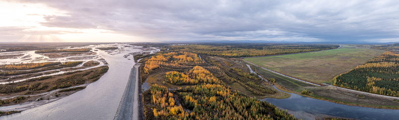 Aerial view of the Moose Creek riverbed surrounded by autumn foliage and vast wilderness under a cloudy sky at sunset in Moose Creek Alaska United States.