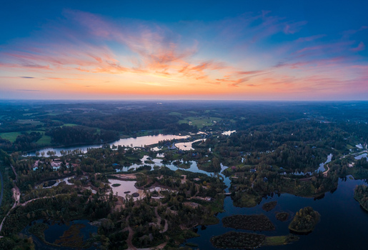 Aerial view of a serene landscape featuring winding lakes and dense forests under a vibrant sunset sky in Latvia. Aerial view of a serene landscape featuring winding lakes and dense forests under a vibrant sunset sky in Latvia.
