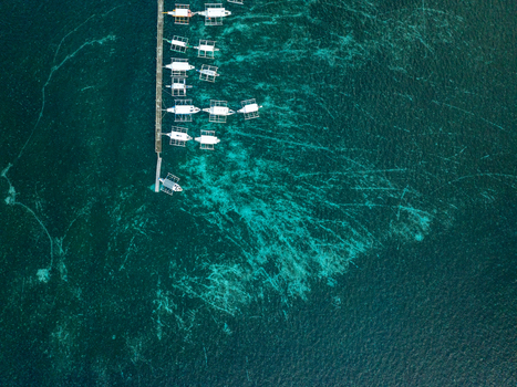 Aerial view of Naked Island with small outrigger boats docked at a wooden pier in the clear turquoise waters of the coral reef in Siargao Philippines. Aerial view of Naked Island with small outrigger boats docked at a wooden pier in the clear turquoise waters of the coral reef in Siargao Philippines.