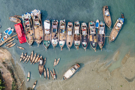 Moheskhali Upazila Bangladesh 11 March 2026 Aerial view of traditional wooden fishing boats moored in the shallow turquoise waters along the coast. Moheskhali Upazila Bangladesh 11 March 2026 Aerial view of traditional wooden fishing boats moored in the shallow turquoise waters along the coast.