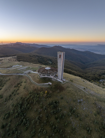 Aerial view of the Buzludzha Monument a brutalist structure with a circular roof and tall tower featuring a red star set against rolling hills in Stara Zagora Bulgaria. Aerial view of the Buzludzha Monument a brutalist structure with a circular roof and tall tower featuring a red star set against rolling hills in Stara Zagora Bulgaria.