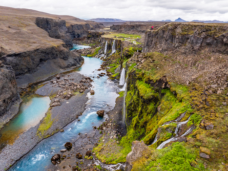 Aerial view of Sigoldufoss waterfall with its turquoise river flowing through a rugged volcanic canyon covered in vibrant green moss in Iceland. Aerial view of Sigoldufoss waterfall with its turquoise river flowing through a rugged volcanic canyon covered in vibrant green moss in Iceland.