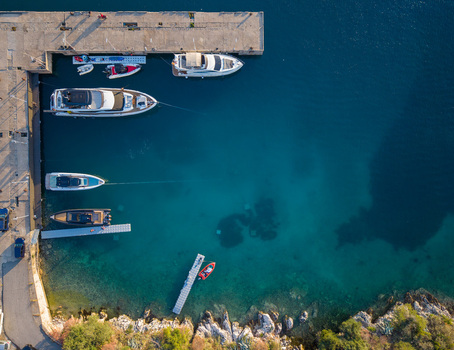 Aerial view of luxury yachts and boats moored at a concrete pier in the turquoise waters of a rocky bay Porto Palermo Qarku i Vlores Albania. Aerial view of luxury yachts and boats moored at a concrete pier in the turquoise waters of a rocky bay Porto Palermo Qarku i Vlores Albania.