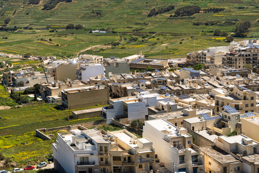 View of traditional limestone buildings with solar panels on rooftops overlooking green terraced fields in Zebbug Gozo Region Malta. View of traditional limestone buildings with solar panels on rooftops overlooking green terraced fields in Zebbug Gozo Region Malta.