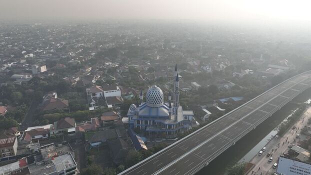 Aerial view of the Al Azhar Mosque surrounded by dense urban housing and a large elevated highway in Bekasi Barat West Java Indonesia. Aerial view of the Al Azhar Mosque surrounded by dense urban housing and a large elevated highway in Bekasi Barat West Java Indonesia.