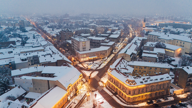 Aerial view of Sremska Mitrovica city center covered in snow with illuminated streets and historic buildings in Sremska Mitrovica Vojvodina Serbia.