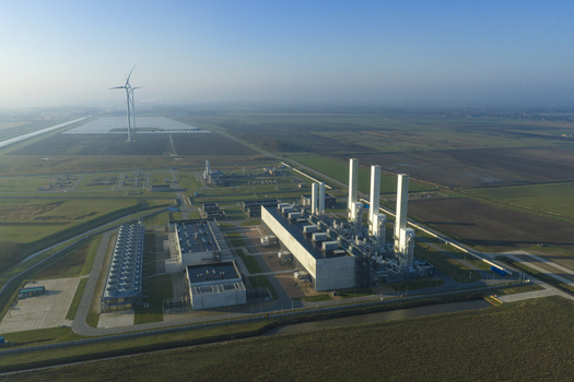 Aerial view of the nitrogen plant with tall white stacks and industrial buildings surrounded by green fields and wind turbines in Zuidbroek Groningen Netherlands. Aerial view of the nitrogen plant with tall white stacks and industrial buildings surrounded by green fields and wind turbines in Zuidbroek Groningen Netherlands.