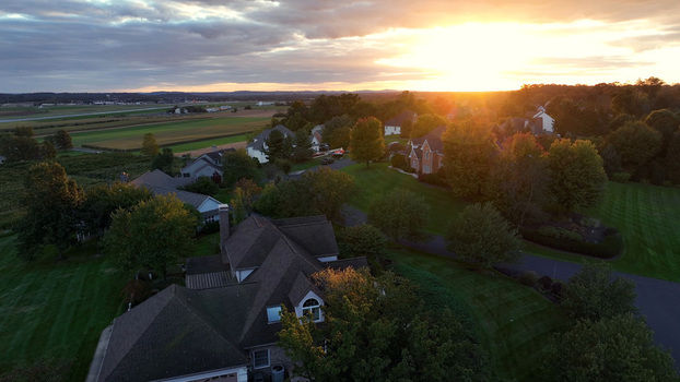 Aerial view of Warwick Township in autumn featuring residential houses lush green lawns and vibrant fall foliage under a warm sunset sky in Rothsville Pennsylvania United States. Aerial view of Warwick Township in autumn featuring residential houses lush green lawns and vibrant fall foliage under a warm sunset sky in Rothsville Pennsylvania United States.