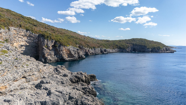Aerial view of the rugged rocky coastline and cliffs along the Adriatic Sea featuring lush green vegetation and clear blue waters in Tivat Tivat Municipality Montenegro. Aerial view of the rugged rocky coastline and cliffs along the Adriatic Sea featuring lush green vegetation and clear blue waters in Tivat Tivat Municipality Montenegro.