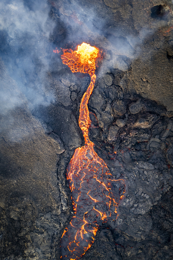 Aerial view of molten lava flowing through the dark rugged landscape creating a fiery spectacle at Sundhn&uacute;kur Eruption Reykjavik Reykjanes Iceland.